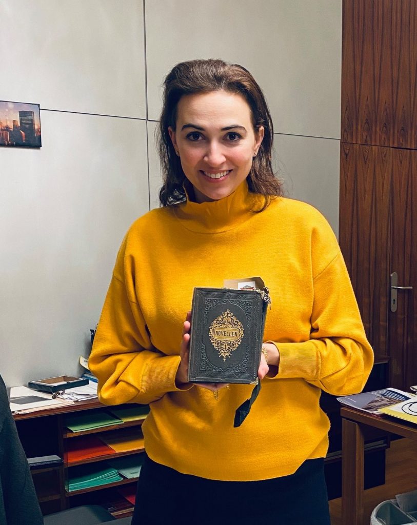 Alma Zadic, Justizministerin von Österreich seit Jänner 2020 mit einer Bernanderl Tasche "Novellen", das aus dem Buch eines ehemaligen Justizministers gefertigt ist.