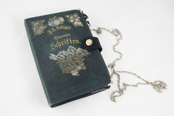 Dirndltasche aus einem Buch von Peter Rosegger mit schönen alpenländischen Verzierungen am Cover kombiniert mit einer schwarzen Krawatte und Edelweißknopf