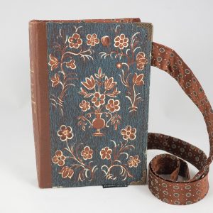 Umhängetäschchen aus einem Buch von Peter Rosegger in mit braunen Blümchen am Cover auf blauem Hintergrund kombiniert mit einer passenden braunen Krawatte