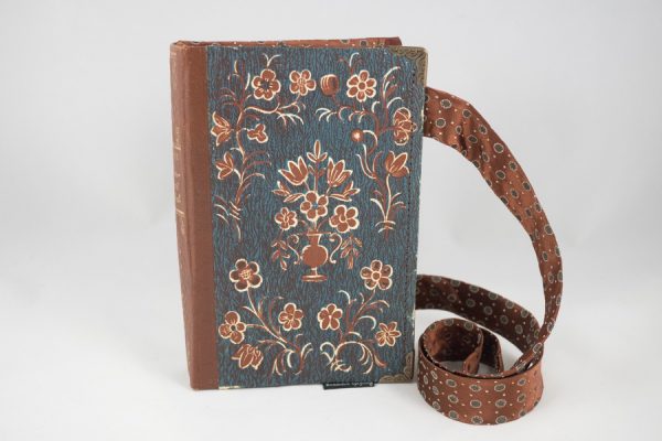 Umhängetäschchen aus einem Buch von Peter Rosegger in mit braunen Blümchen am Cover auf blauem Hintergrund kombiniert mit einer passenden braunen Krawatte