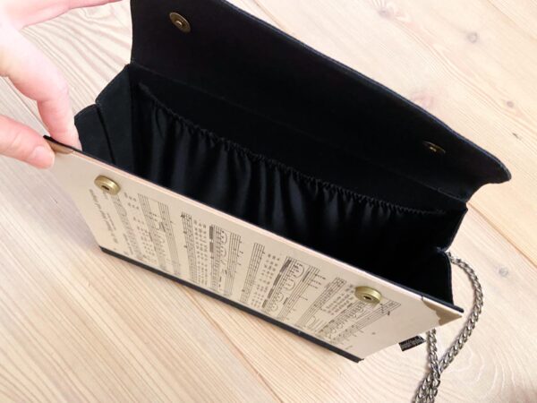 Clutch aus Notenblättern mit schwarzer Lasche als Verschluss