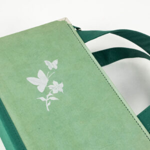 Tasche aus einem Buch "Jugend" in grün mit silberner Blume und Schmetterlingen am Cover kombiniert mit grünem Stoff und Reißverschluss sowie silbernen Metallelementen