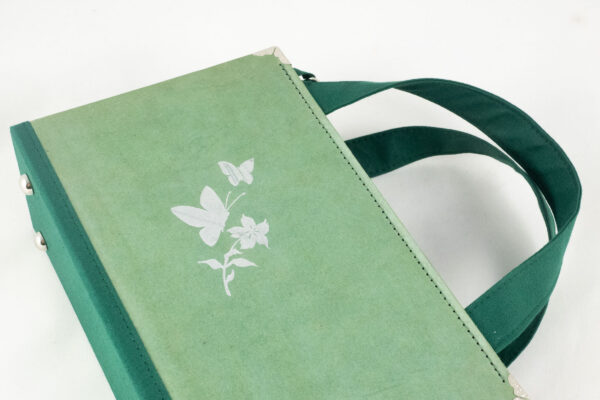 Tasche aus einem Buch "Jugend" in grün mit silberner Blume und Schmetterlingen am Cover kombiniert mit grünem Stoff und Reißverschluss sowie silbernen Metallelementen