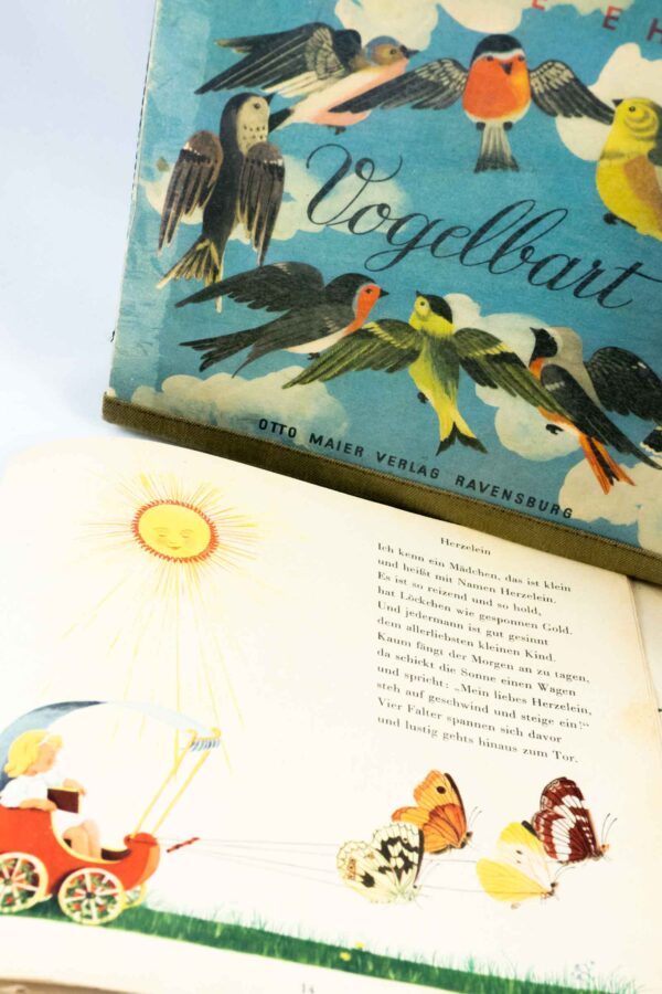 Tasche aus einem Vintage Kinderbuch "Vogelbart" mit blauem Buchcover und vielen Vögel darauf, kombiniert mit schwarzem Stoff und einer schwarzen Krawatte, die Vogelfedern abbildet.