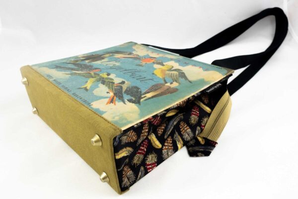 Tasche aus einem Vintage Kinderbuch "Vogelbart" mit blauem Buchcover und vielen Vögel darauf, kombiniert mit schwarzem Stoff und einer schwarzen Krawatte, die Vogelfedern abbildet.