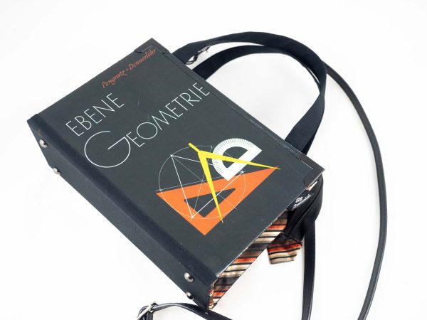 Tasche aus einem Geometrie-Lehrbuch in Schwarz mit Lineal und Zirkel am Cover kombiniert mit schwarz/gelb/orange gestreifter Krawatte