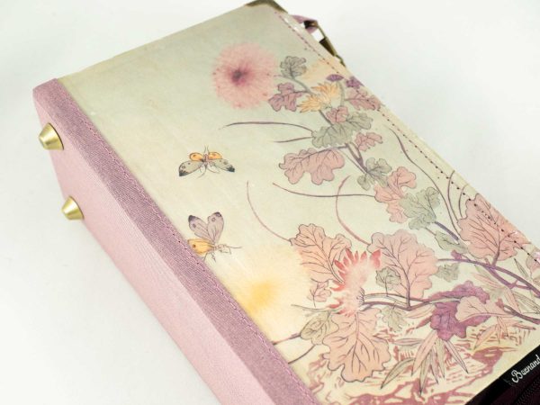 Taschen aus einem Buch von Pearl S. Buck mit rosa/lila Blumen am Cover, kombiniert mit rosa/lila schimmernder Krawatte
