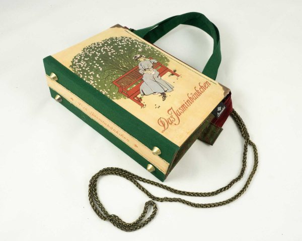Tasche aus einem Buch "Jasminbänckchen" mit einer Dame auf einer Parkbank sitzend, dahinter ein Jasmin-Busch, kombiniert mit grün/roter Krawatte und grünem Stoff, rotem Reißverschluss