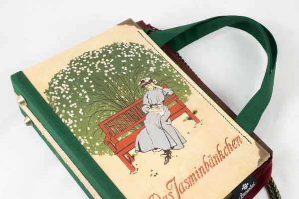 Tasche aus einem Buch "Jasminbänckchen" mit einer Dame auf einer Parkbank sitzend, dahinter ein Jasmin-Busch, kombiniert mit grün/roter Krawatte und grünem Stoff, rotem Reißverschluss