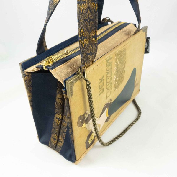 Tasche aus einem alten Buch "Der Trotzkopf" in beige. Am Cover ist eine Frau, die ein Hündchen in die Höhe hält, zu sehen. Buch kombiniert mit einer dunkelblau/goldenen Krawatte und goldenem Stoff.