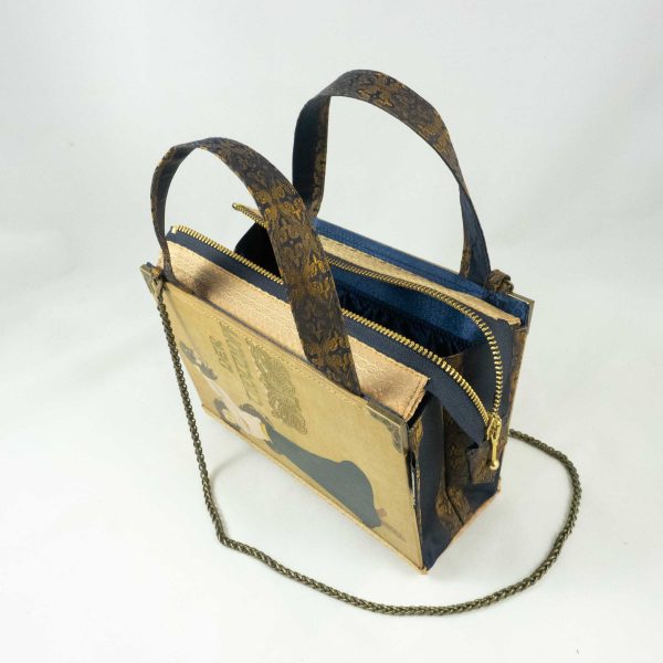 Tasche aus einem alten Buch "Der Trotzkopf" in beige. Am Cover ist eine Frau, die ein Hündchen in die Höhe hält, zu sehen. Buch kombiniert mit einer dunkelblau/goldenen Krawatte und goldenem Stoff.