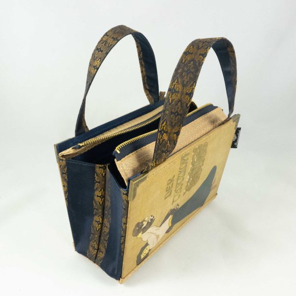 Tasche aus einem alten Buch "Der Trotzkopf" in beige. Am Cover ist eine Frau, die ein Hündchen in die Höhe hält, zu sehen. Buch kombiniert mit einer dunkelblau/goldenen Krawatte und goldenem Stoff.