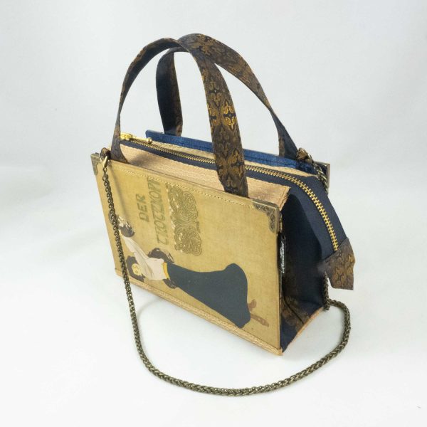 Tasche aus einem alten Buch "Der Trotzkopf" in beige. Am Cover ist eine Frau, die ein Hündchen in die Höhe hält, zu sehen. Buch kombiniert mit einer dunkelblau/goldenen Krawatte und goldenem Stoff.