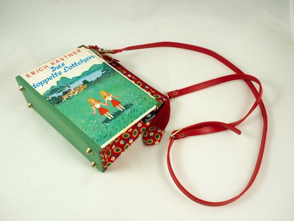 Tasche aus einem Buch von Erich Kästner "Das doppelte Lottchen" mit den Zwillingen am Cover auf einer grünen Wiese, kombiniert mit einer rot/grün/blau blumig gemusterten Krawatte, roter Taschenriemen