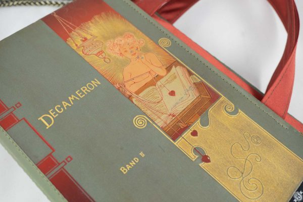 Tasche aus einem Buch von Boccaccio's Decameron im grauen Cover mit eine Dame drauf, die ein Herz über einem Buch baumeln läasst. Goldelemente und dunkelorange, kombiniert mit einer dunkelorangen Krawatte