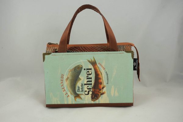 Tasche aus einem Buch "Der letzte Schrei" mit zwei Fischen am Cover in hellblau und goldbraun gehalten, kombiniert mit einer Krawatte in goldbrauner Farbe, die auch Fische abbildet.