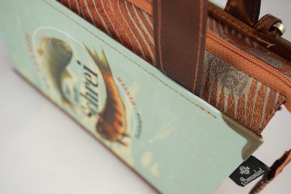 Tasche aus einem Buch "Der letzte Schrei" mit zwei Fischen am Cover in hellblau und goldbraun gehalten, kombiniert mit einer Krawatte in goldbrauner Farbe, die auch Fische abbildet