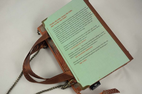 Tasche aus einem Buch "Der letzte Schrei" mit zwei Fischen am Cover in hellblau und goldbraun gehalten, kombiniert mit einer Krawatte in goldbrauner Farbe, die auch Fische abbildet