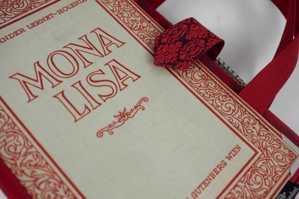 Tasche aus einem Buch "Mona Lisa" mit schönen roten Verzierungen rundum, kombiniert mit einer rot gemusterten Krawatte